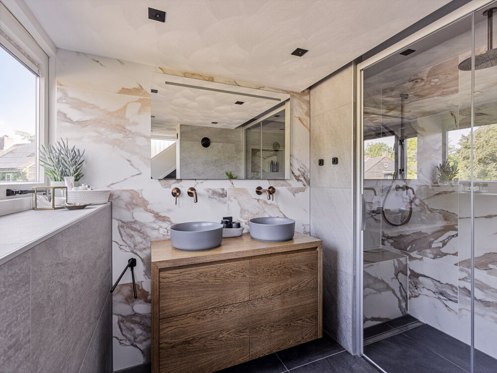 Moderne badkamer met marmerlook muur, 2 waskommen en een douche